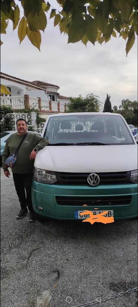 Cliente junto a su furgoneta bicolor delante de una casa